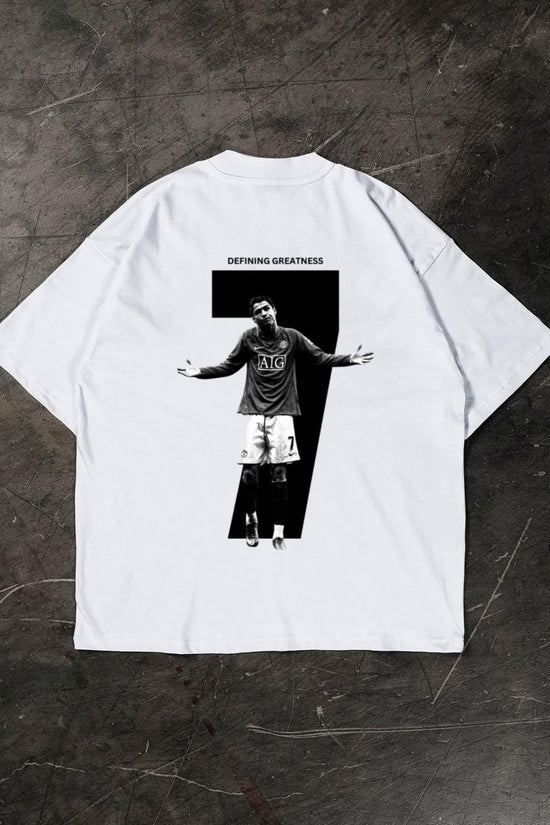 White t-shirt with a graphic of a Cristiano Ronaldo and 'Defying Greatness' text on a dark textured surface